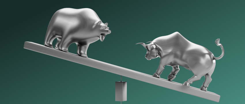 A silver bull and bear balance on a seesaw, symbolizing market sentiment and market dynamics. The bear is elevated while the bull is lower, set against a green background.