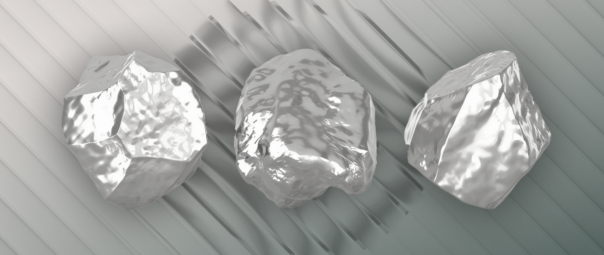 Three shiny metallic nuggets resting on a diagonal striped background, illustrating raw precious metals in a White Gold vs Silver comparison.