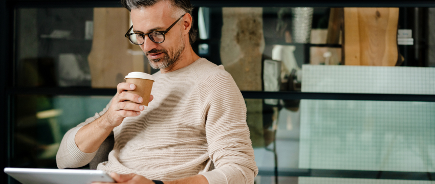 Trader with a coffee reviewing figures on a tablet before placing a EUR/USD trade